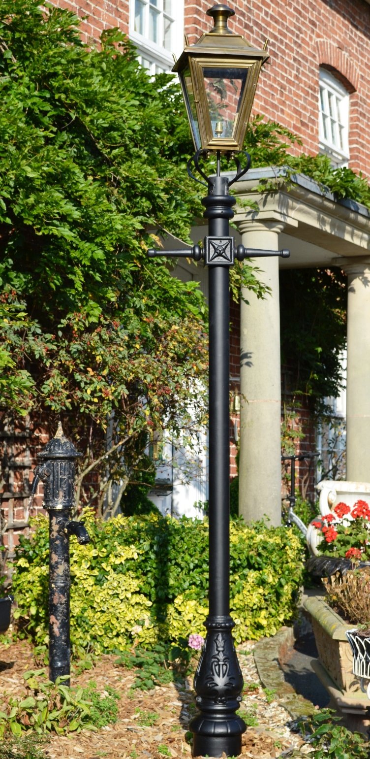 Antique brass lamp post in flower bed