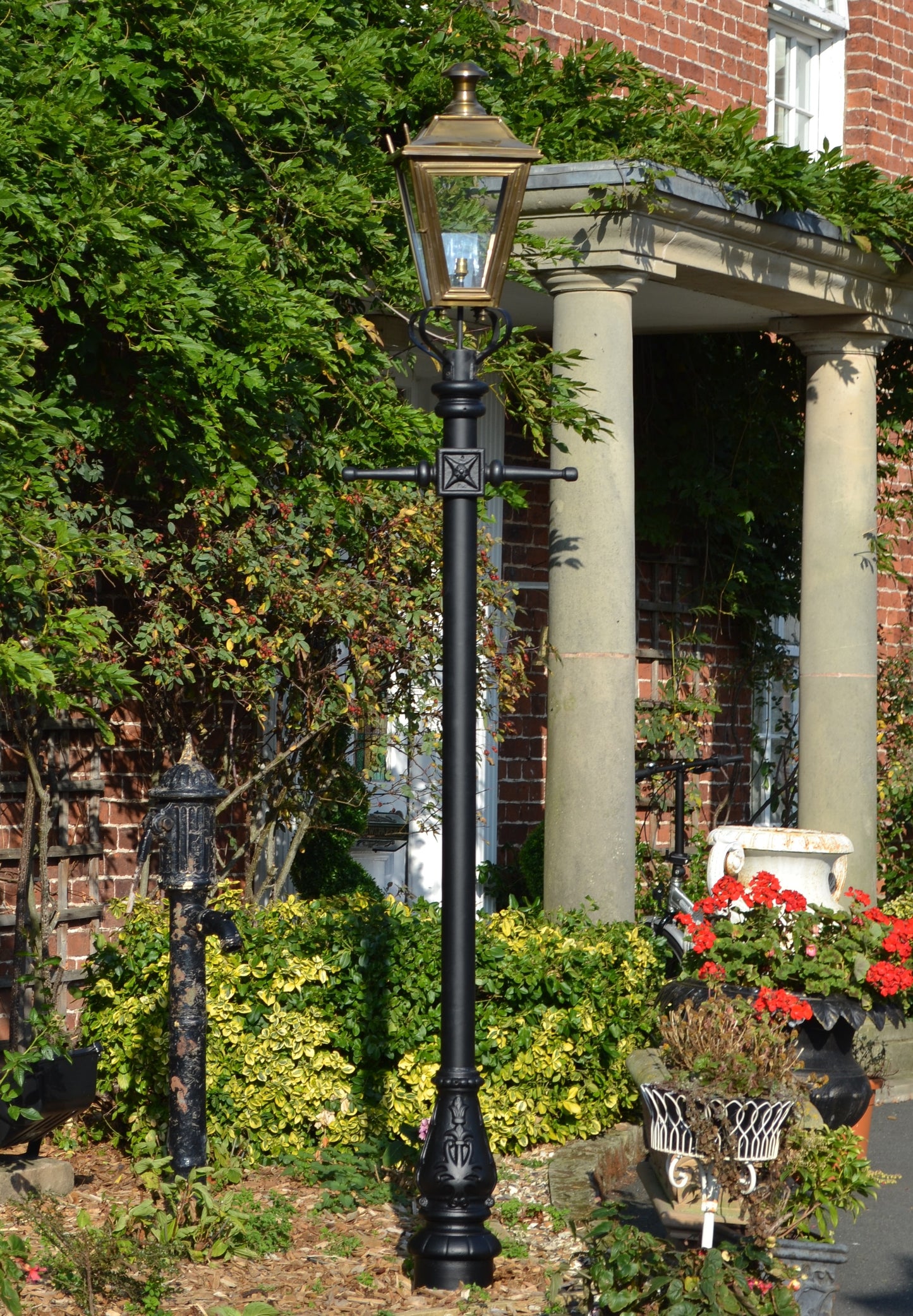 Antique brass lamp post in flower bed