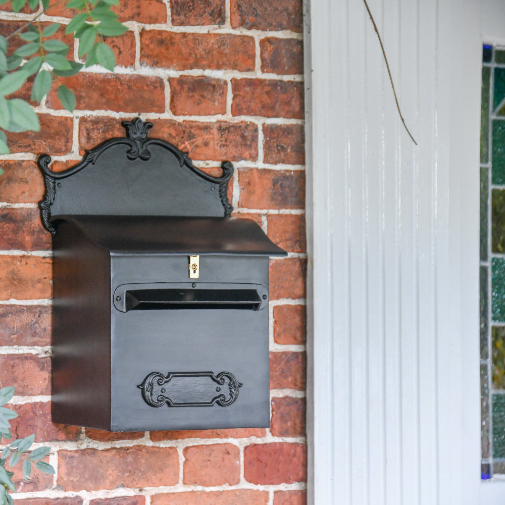 The black post box wall mounted to a brick wall