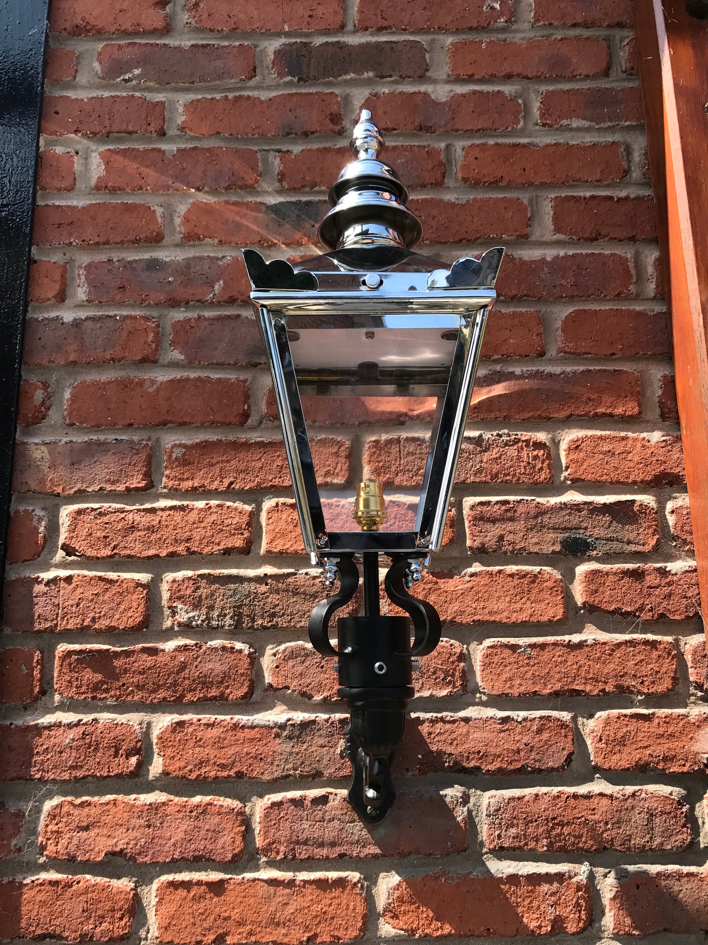 Chrome wall lantern attached to red bricks 