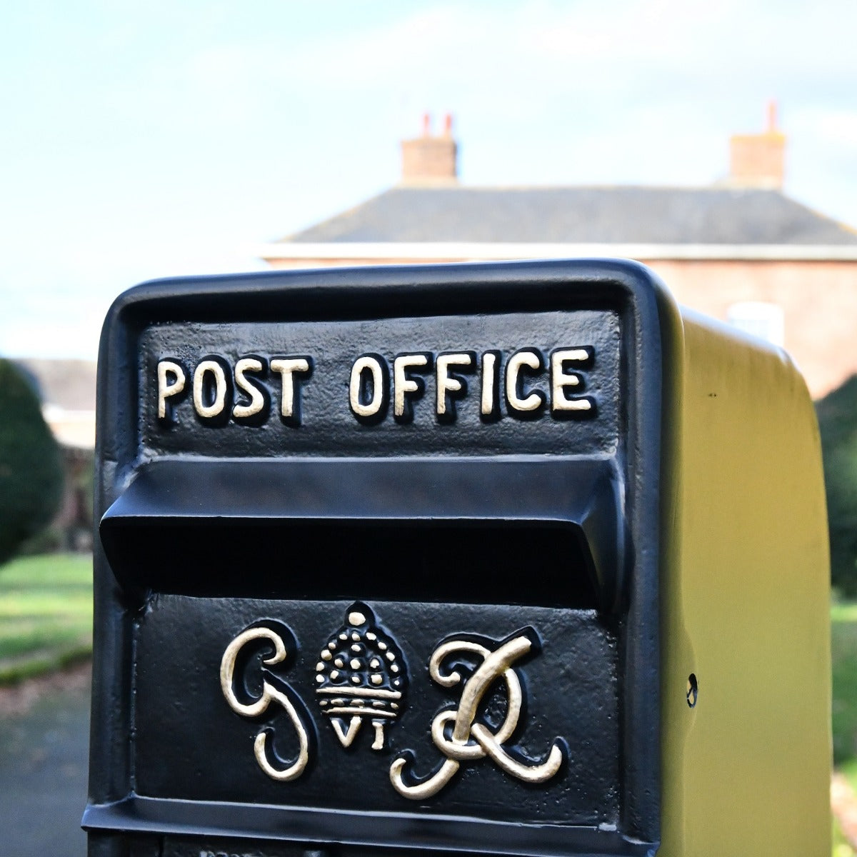 Close up of gold lettering on black King George post box 