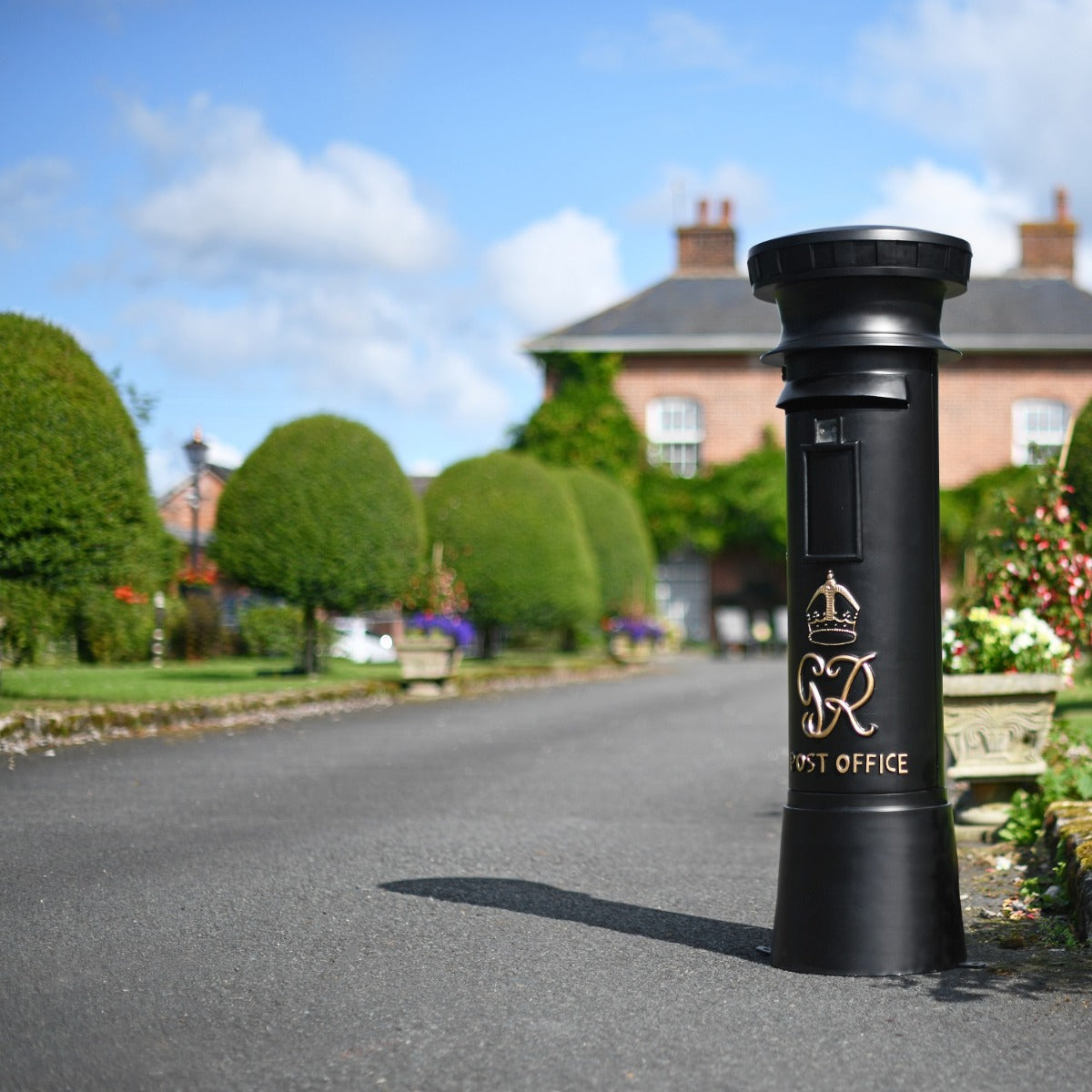 Black Traditional GR Pillar Post Box in driveway setting 