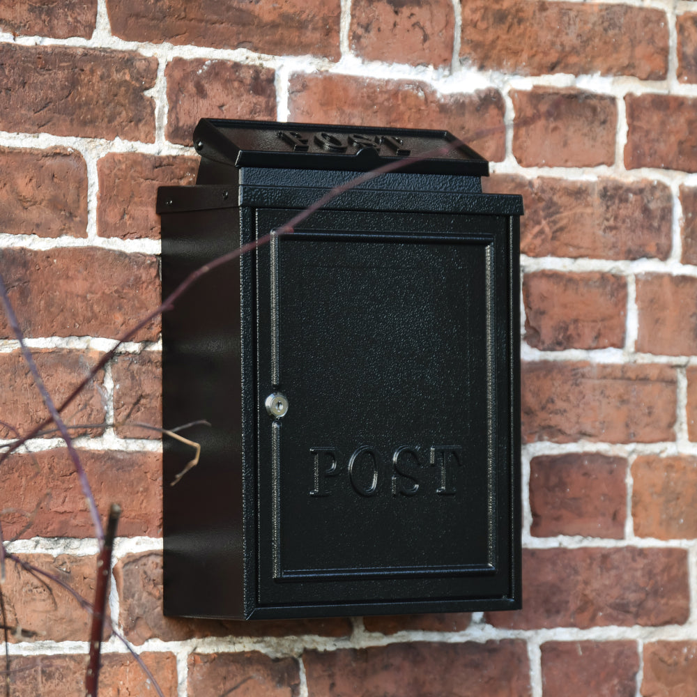 Post box mounted on to a red brick wall 
