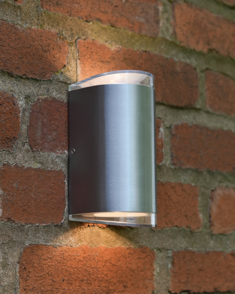 Angled view of the wall light lit up on a brick wall