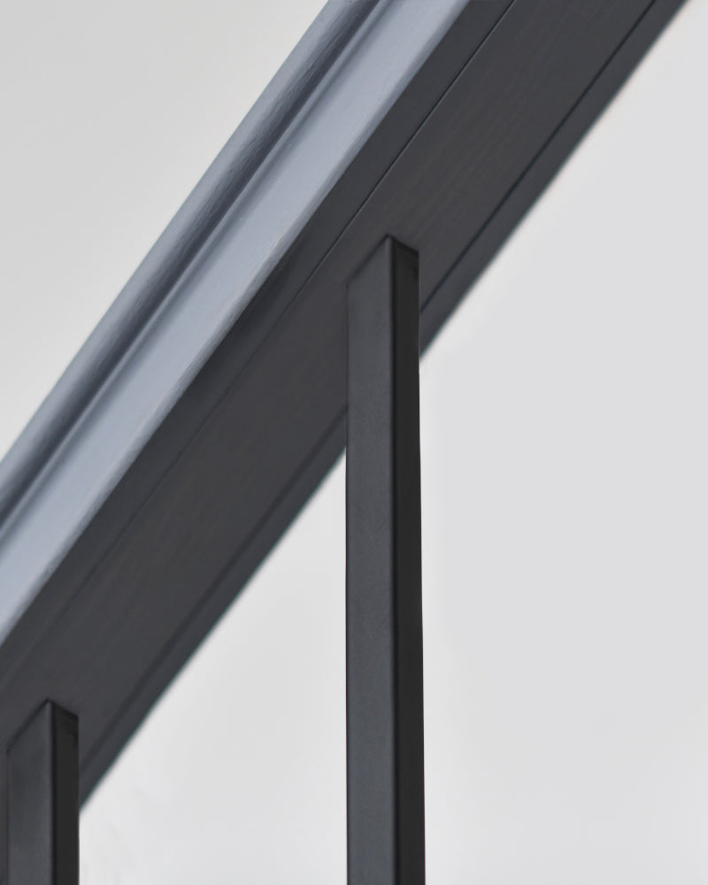 Black stair spindle attached to the top of the bannister 