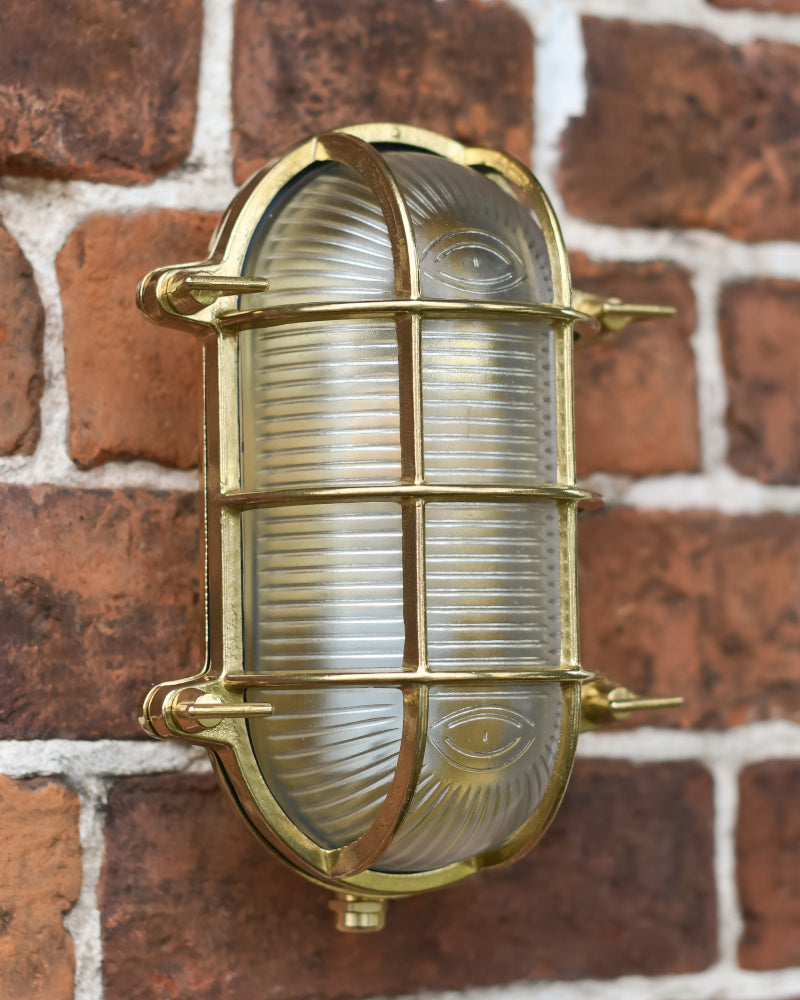 The antique brass outdoor light mounted to a red brick wall 