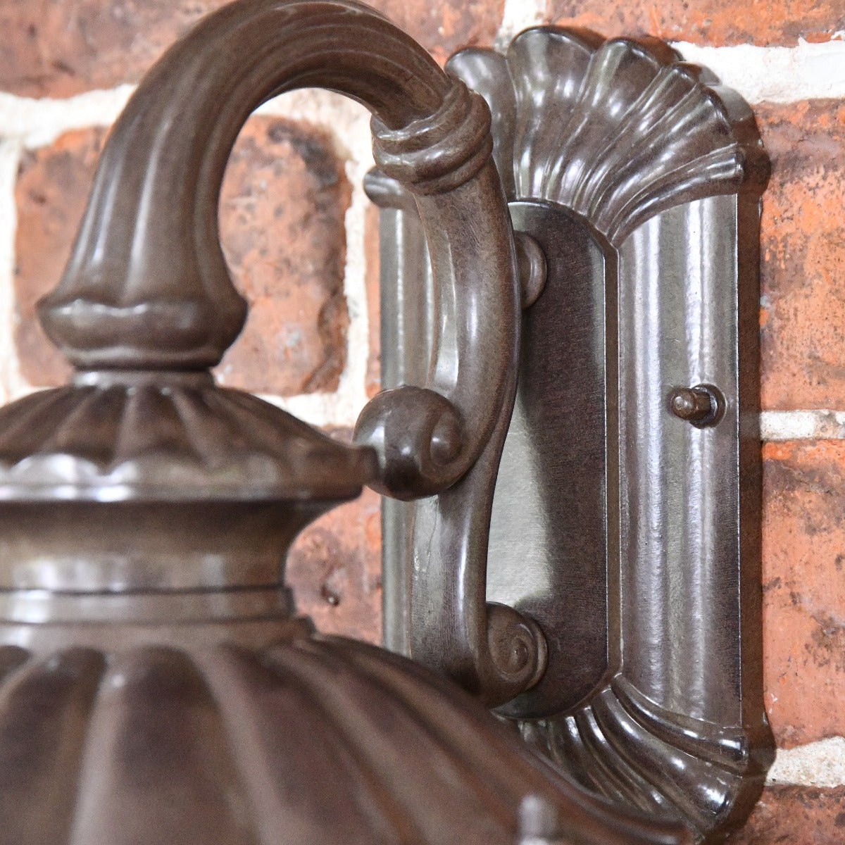 Close up of wall mounted bracket and filigree curved arm 