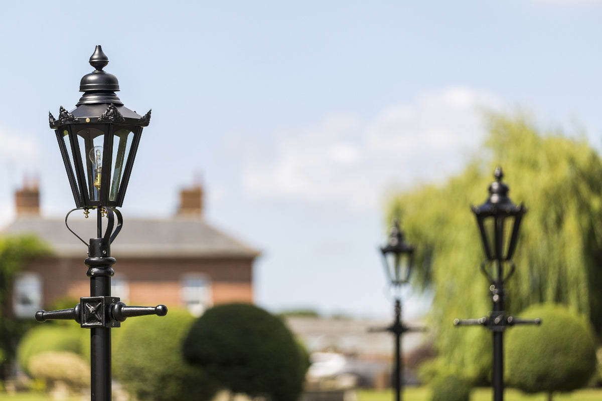 A trio of used small Victorian lamp posts on a driveway 