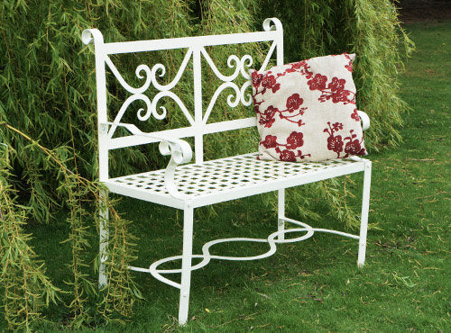 white solid iron bench in the garden with cushion